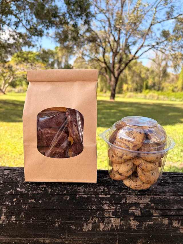 A kraft bag of Espresso Glazed Brownies beside a Brownie Points cup outdoors.