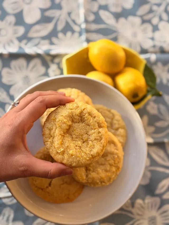 A close-up handheld photo of a Forever Favourites_Zesty Cookie with lemons in the background.