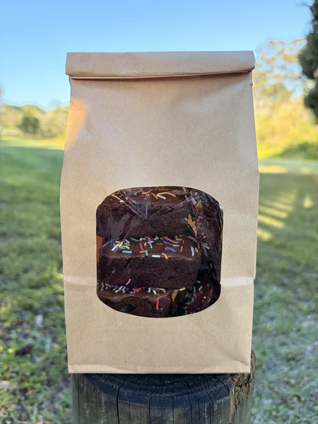 Glazed Fudgy Brownies with colourful sprinkles packaged in a kraft paper bag.
