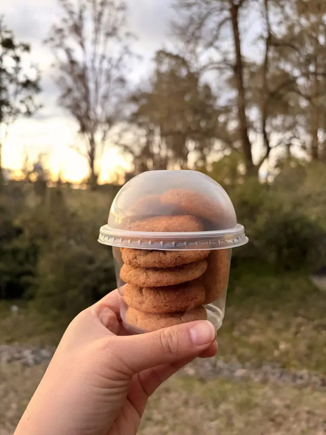 A cup filled with Cinnamon Hug treat-size cookies beside tea and lemon.