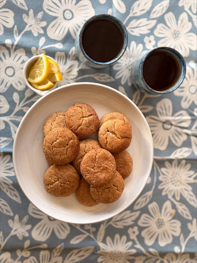 An overhead view of Cinnamon Hug treat-size cookies served with tea and lemon.