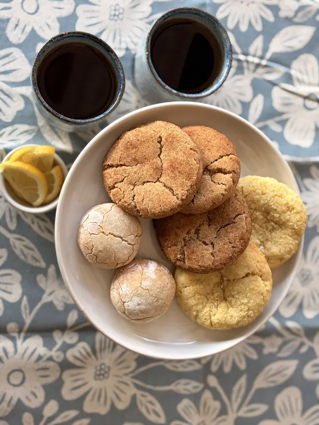 An overhead assortment of Cinnamon Hug, Almond Kiss, and Zesty Cookies served with tea.