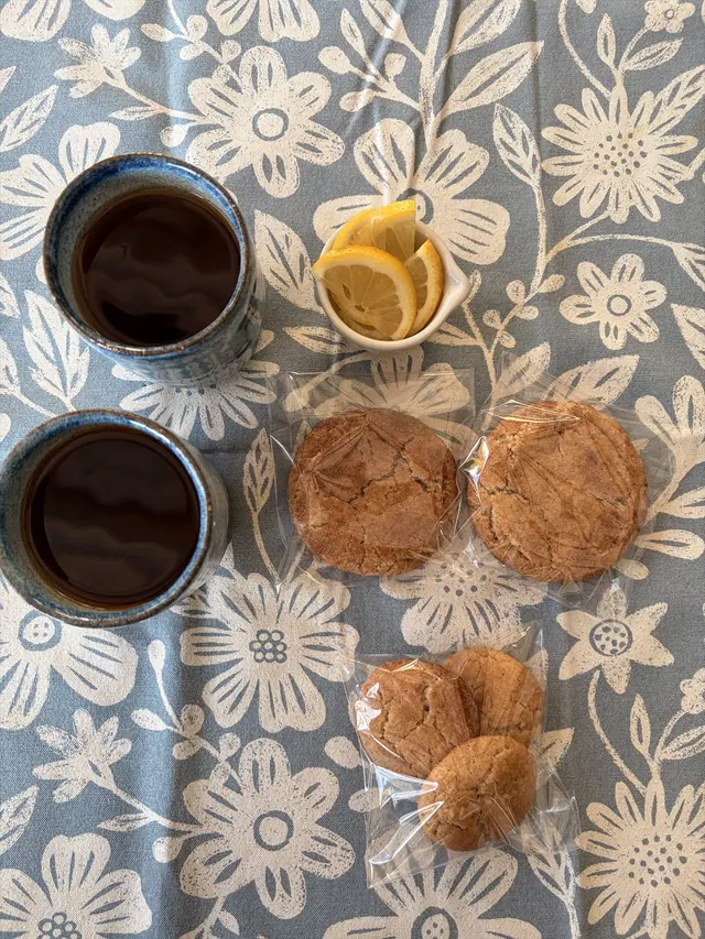 Cinnamon Hug cookies individually packaged beside two cups of tea.