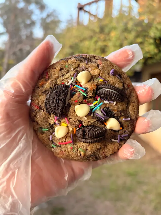 A close-up of a Forever Favourite Happy Cookie held outdoors.