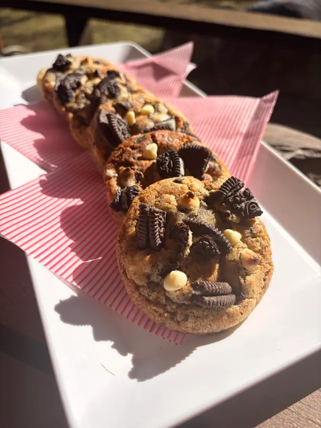 Cookies & Cream signature cookies on a white tray outdoors.